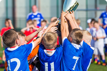 Players on soccer field celebrating with trophy